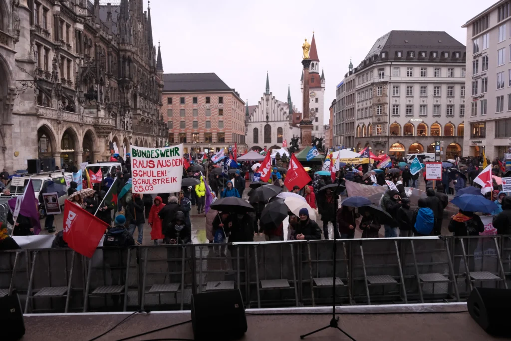 Marienplatz meydanında yağmur altında toplanan kalabalık.